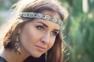 Portrait of a young female hippie with headband and earrings